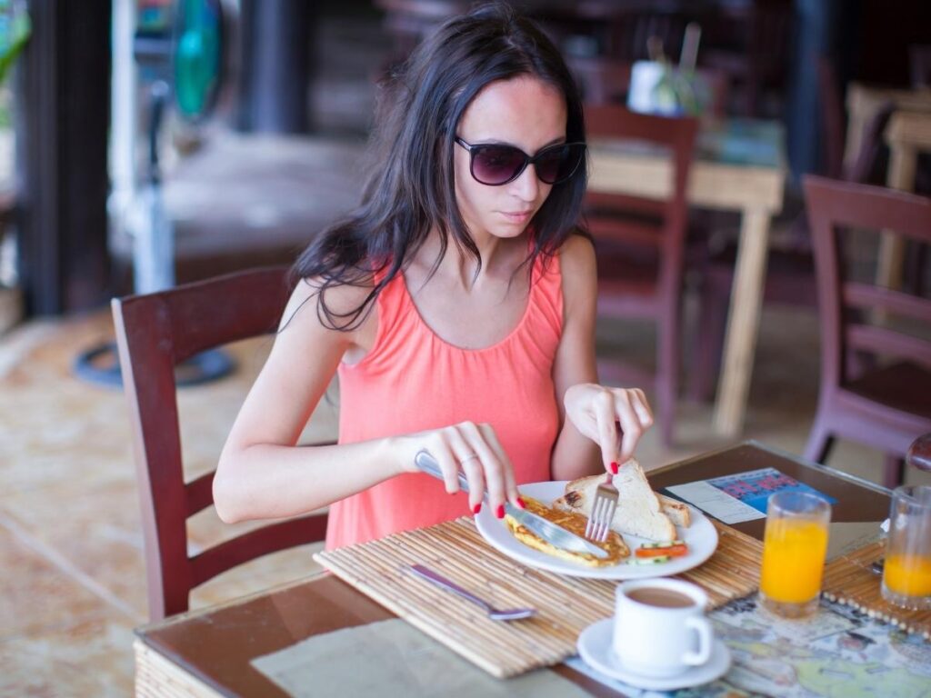 Traveler having breakfast at an outdoor cafe in morning sunlight after an international flight