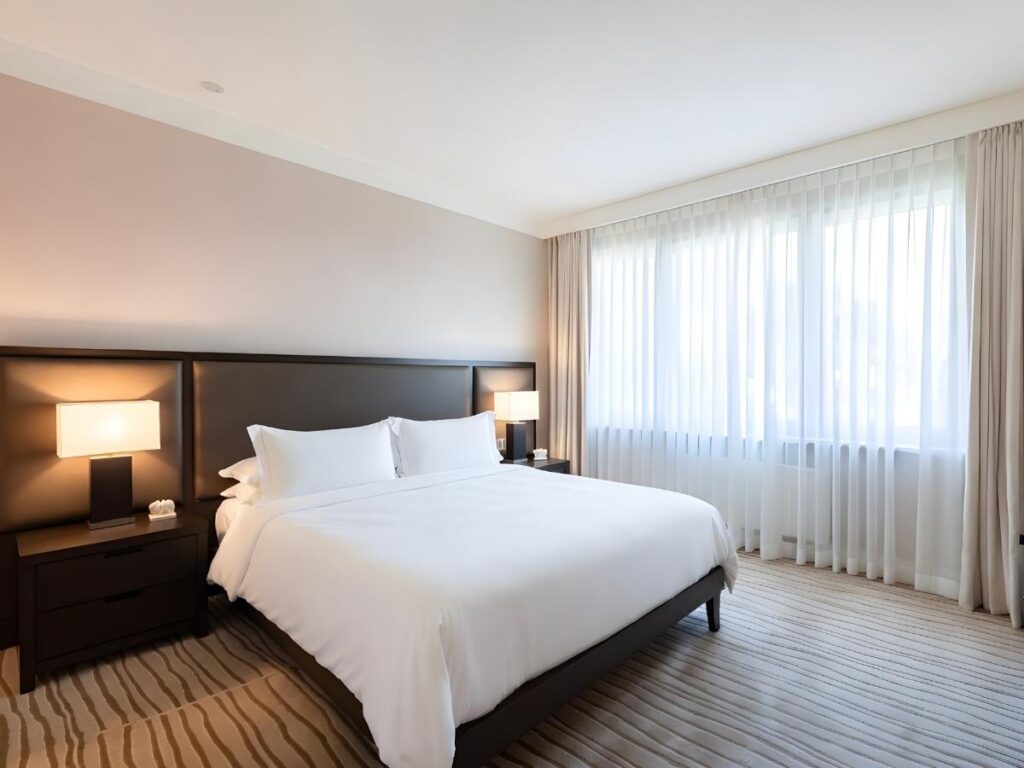 Neatly made hotel bed with white pillows and soft lighting in a cozy hotel room