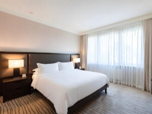 Neatly made hotel bed with white pillows and soft lighting in a cozy hotel room