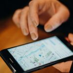 Person holding a smartphone with Google Maps open showing a city neighborhood map while planning a trip