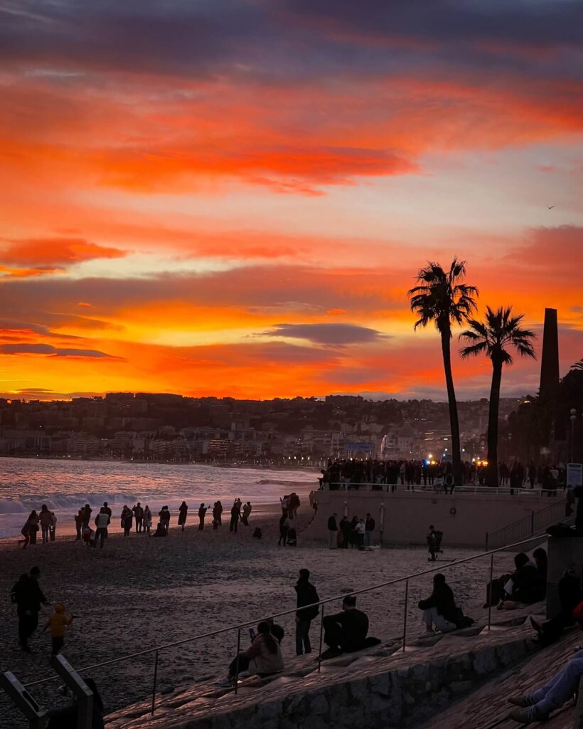 Sunset along the Promenade des Anglais with people sitting by the sea