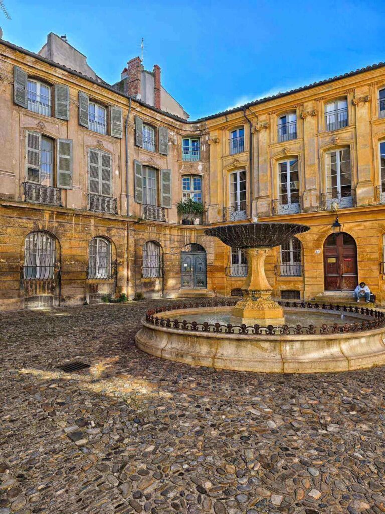 Fountain in Aix-en-Provence with people sitting at cafés and relaxed street atmosphere