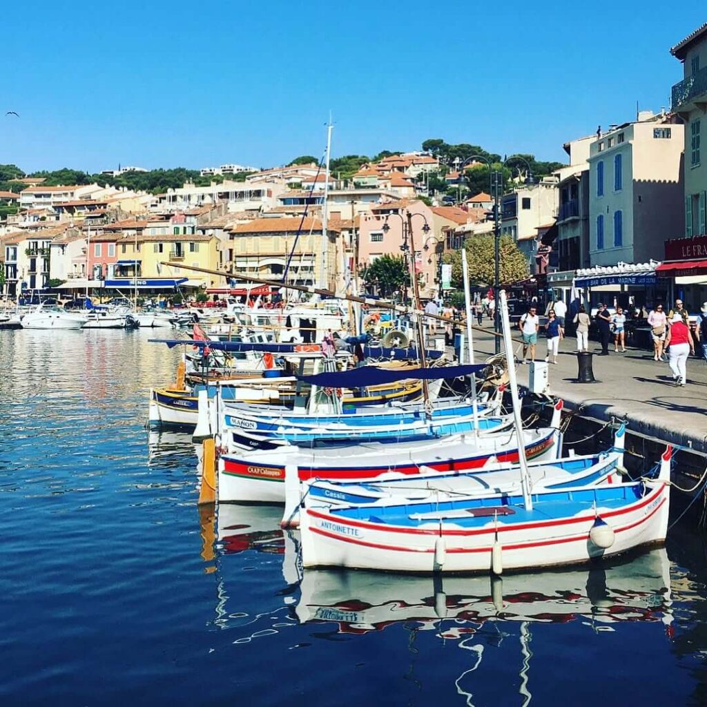 Busy summer scene at Cassis harbor with crowds and restaurants