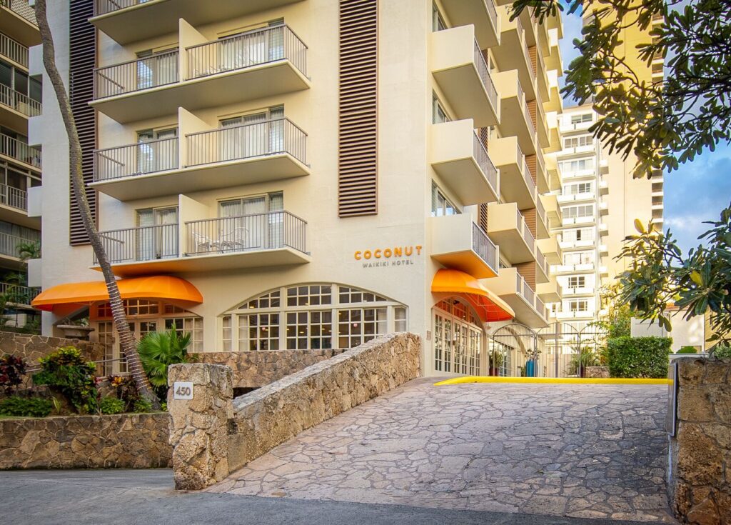 Exterior view of Coconut Waikiki Hotel in Waikiki, featuring a boutique hotel setting, canal-side location, modern tropical decor, and a relaxed atmosphere near the beach and city attractions.