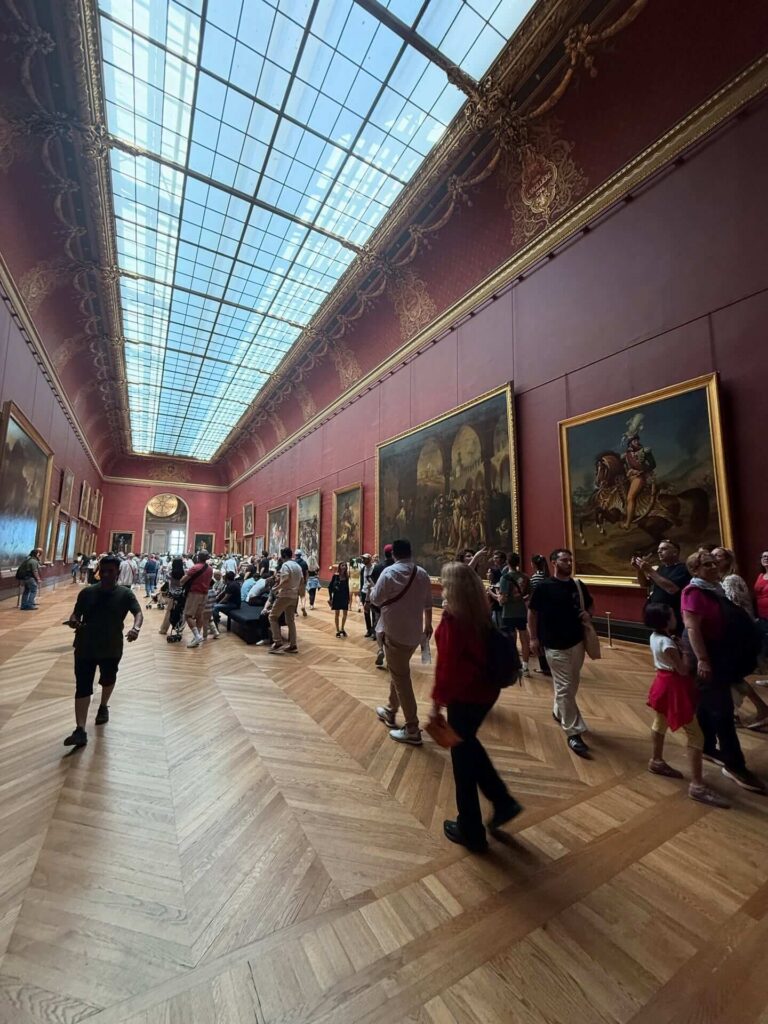 Busy gallery inside the Denon Wing of the Louvre Museum with visitors