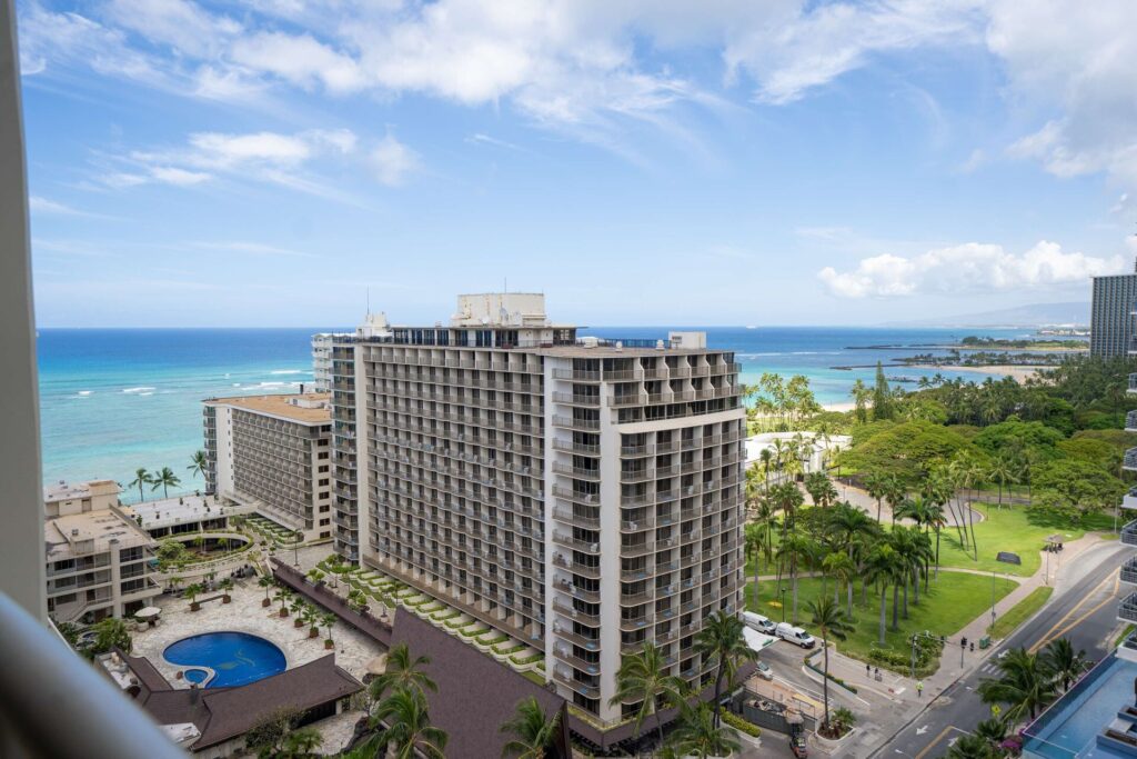 Exterior view of Embassy Suites by Hilton Waikiki Beach Walk in Waikiki, featuring modern all-suite accommodations, open-air atrium, nearby shopping and dining, and a short walk to the beach.