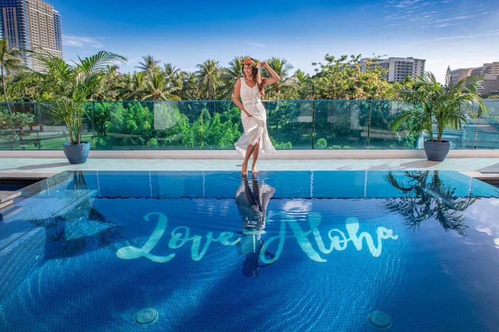 Exterior view of Hotel La Croix in Waikiki, featuring a boutique high-rise design, stylish interiors, city and mountain views, and a relaxed tropical atmosphere near the beach.