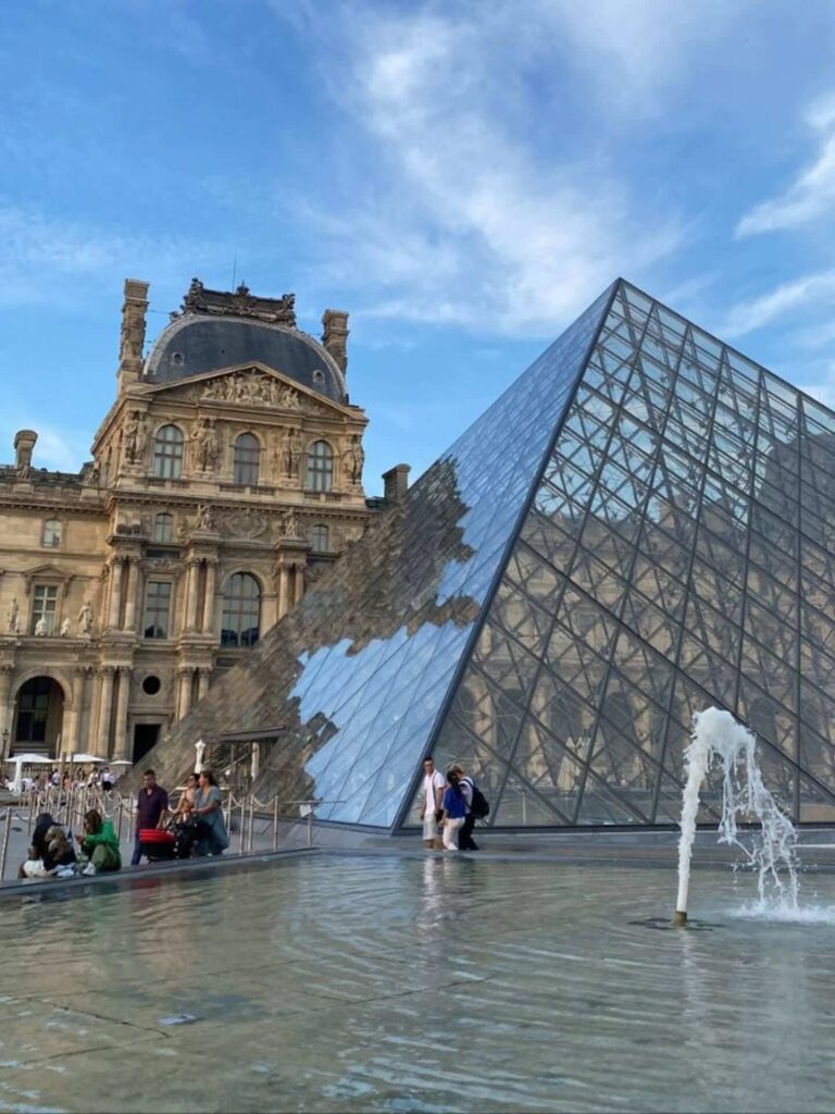 Visitors relaxing in the Louvre courtyard near the glass pyramid