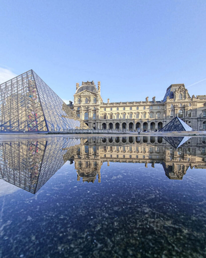 Louvre Museum pyramid courtyard in the early morning with few visitors