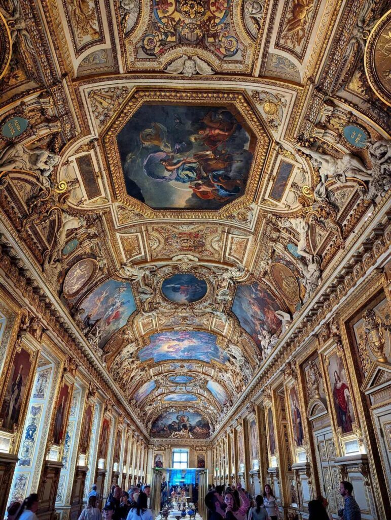Wide interior gallery inside the Louvre Museum showing its large scale