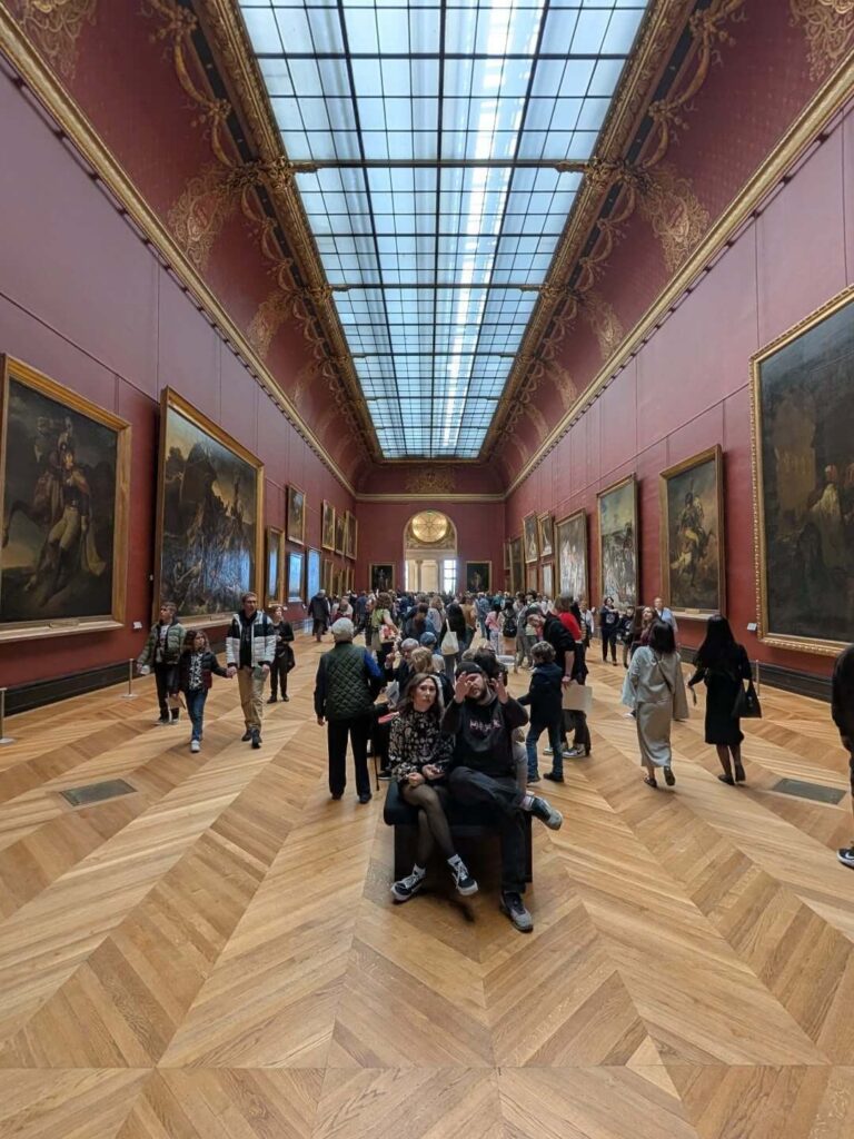 Visitors sitting and resting inside the Louvre Museum