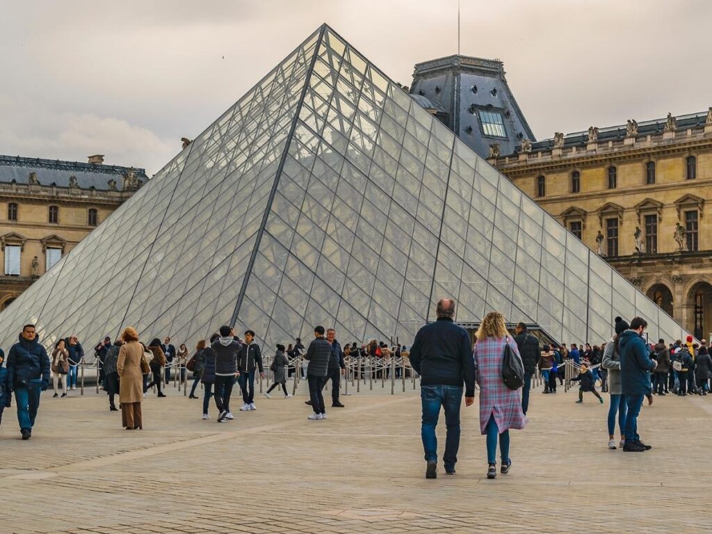 Crowds and queues at the Louvre pyramid entrance during the day
