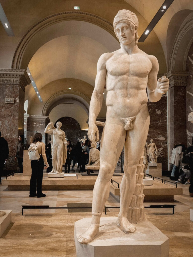 Sculptures displayed inside a light-filled gallery at the Louvre Museum