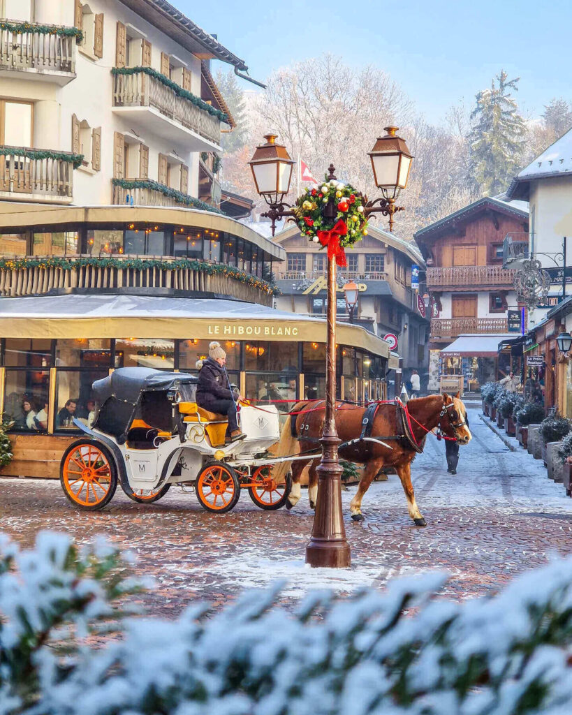 Horse-drawn carriage ride through snowy Megève village in the evening