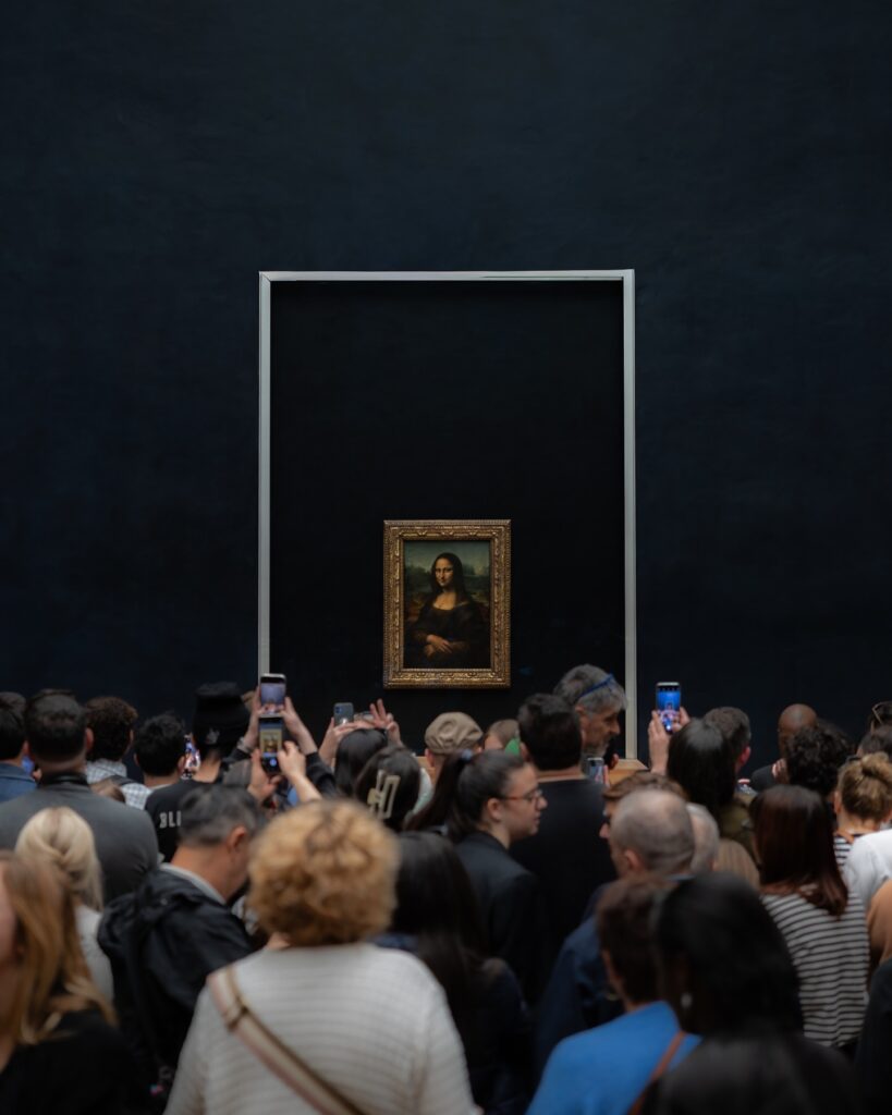 Crowd of visitors gathered around the Mona Lisa inside the Louvre Museum
