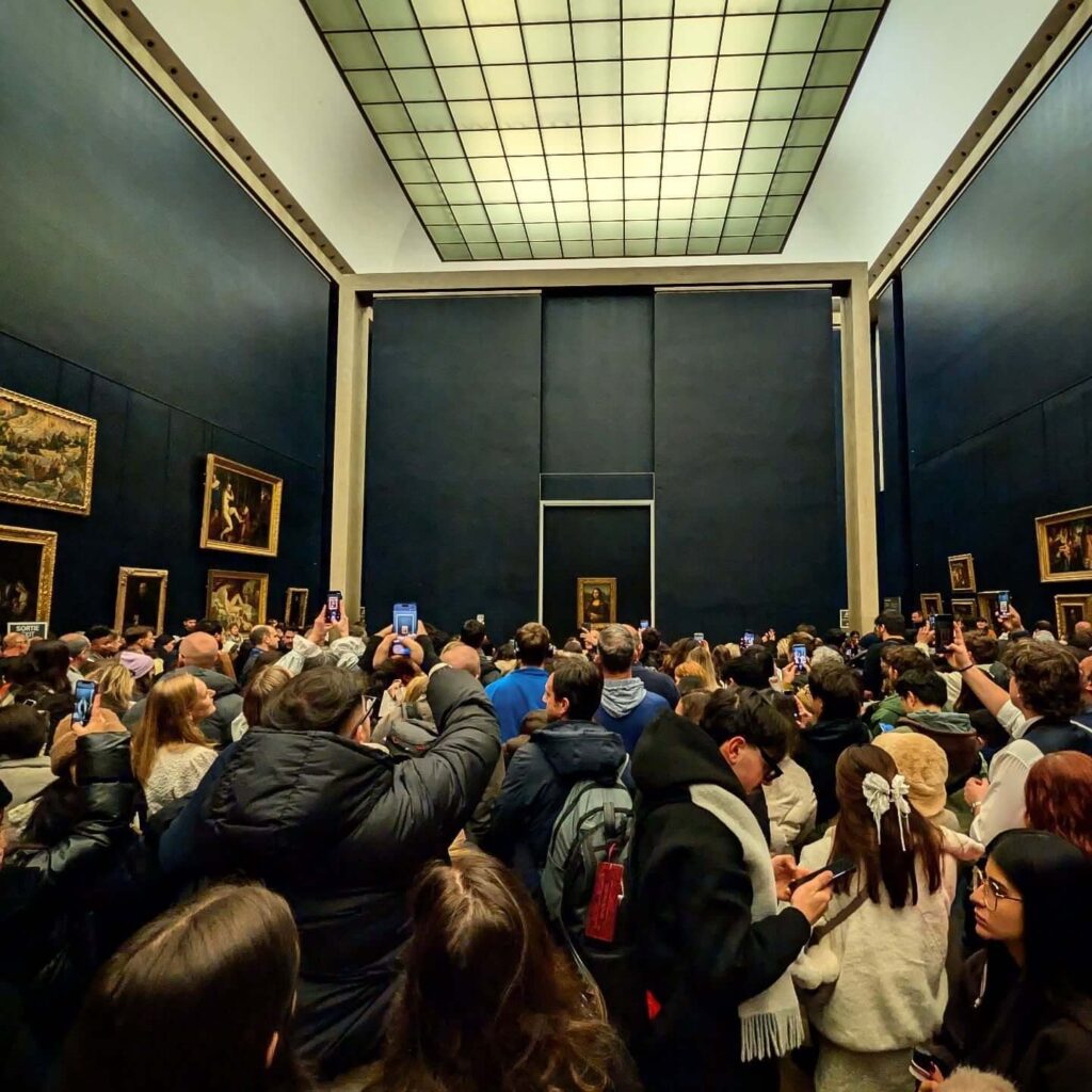 Visitors moving toward the Mona Lisa room inside the Louvre Museum