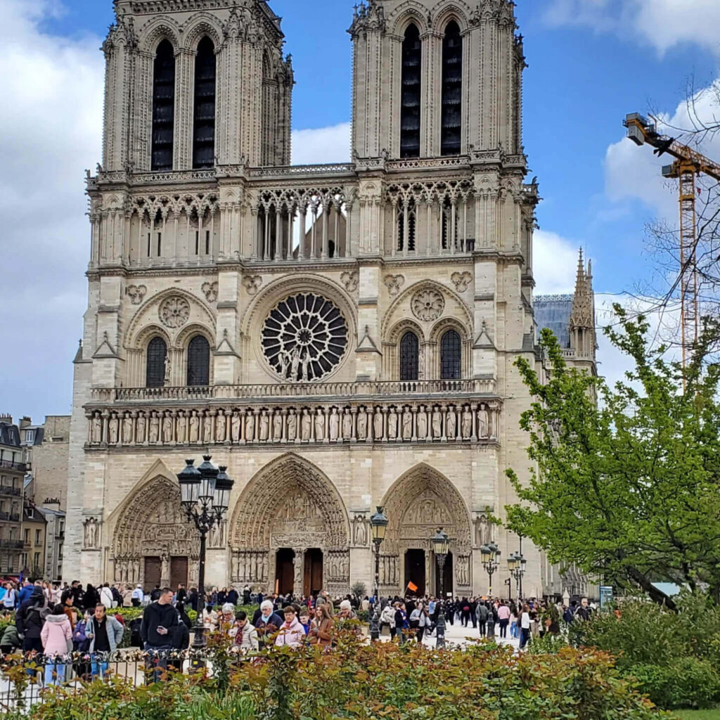 Visitors near Notre Dame de Paris exterior during restoration with limited access