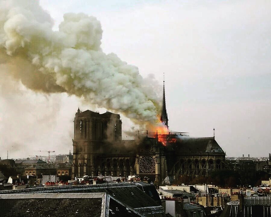 Notre Dame cathedral during the 2019 fire with flames and collapsing spire