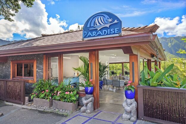 Exterior view of Paradise Bay Resort in Oahu, featuring a serene waterfront setting, lush tropical mountains, marina views, and peaceful boutique resort ambiance.