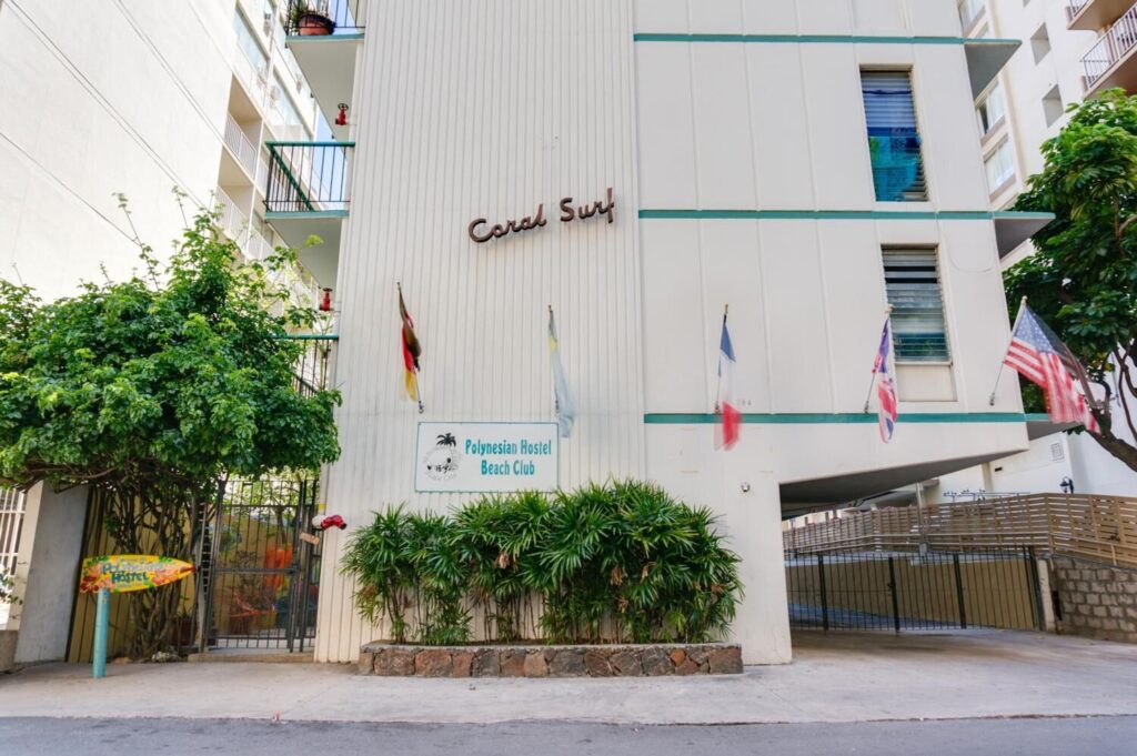 Exterior view of Polynesian Hostel Beach Club in Waikiki, featuring a budget-friendly hostel, laid-back social atmosphere, colorful decor, and close proximity to the beach.