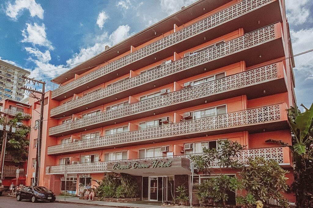 Exterior view of Royal Grove Waikiki in Waikiki, featuring a charming budget-friendly hotel with tropical greenery, outdoor pool, and a relaxed island-style atmosphere near the beach.