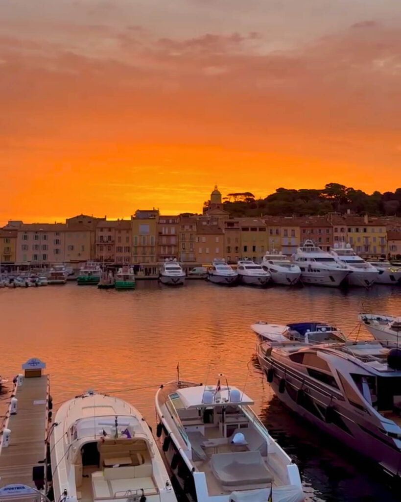 Calm sunset view of Saint Tropez harbor with reflections on the water