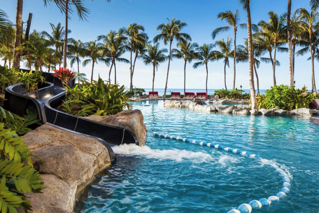 Exterior view of Sheraton Waikiki in Waikiki, featuring a beachfront high-rise tower, infinity pool overlooking the Pacific Ocean, and vibrant resort atmosphere.