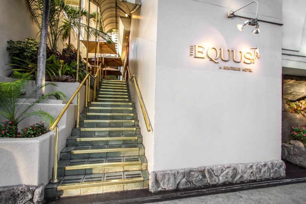 Exterior view of The Equus in Waikiki, featuring boutique-style accommodations, equestrian-themed decor, a cozy pool area, and a relaxed, intimate atmosphere near the beach.
