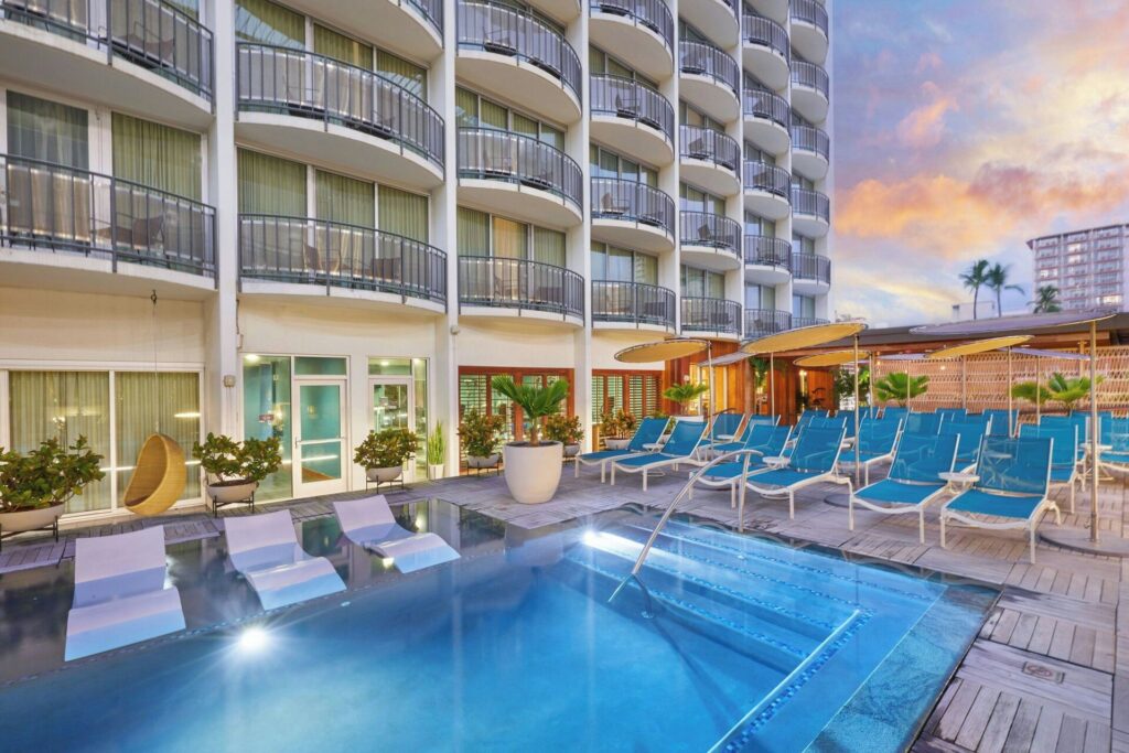 Exterior view of The Laylow, Autograph Collection in Waikiki, featuring mid-century modern design, lush tropical landscaping, stylish outdoor lounge areas, and a relaxed boutique luxury atmosphere.