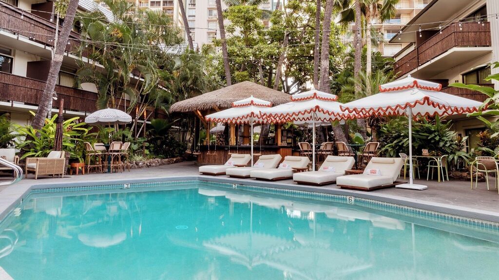 Exterior view of White Sands Hotel in Waikiki, featuring a retro boutique vibe, tropical courtyard pool, lush greenery, and a relaxed island atmosphere near the beach.