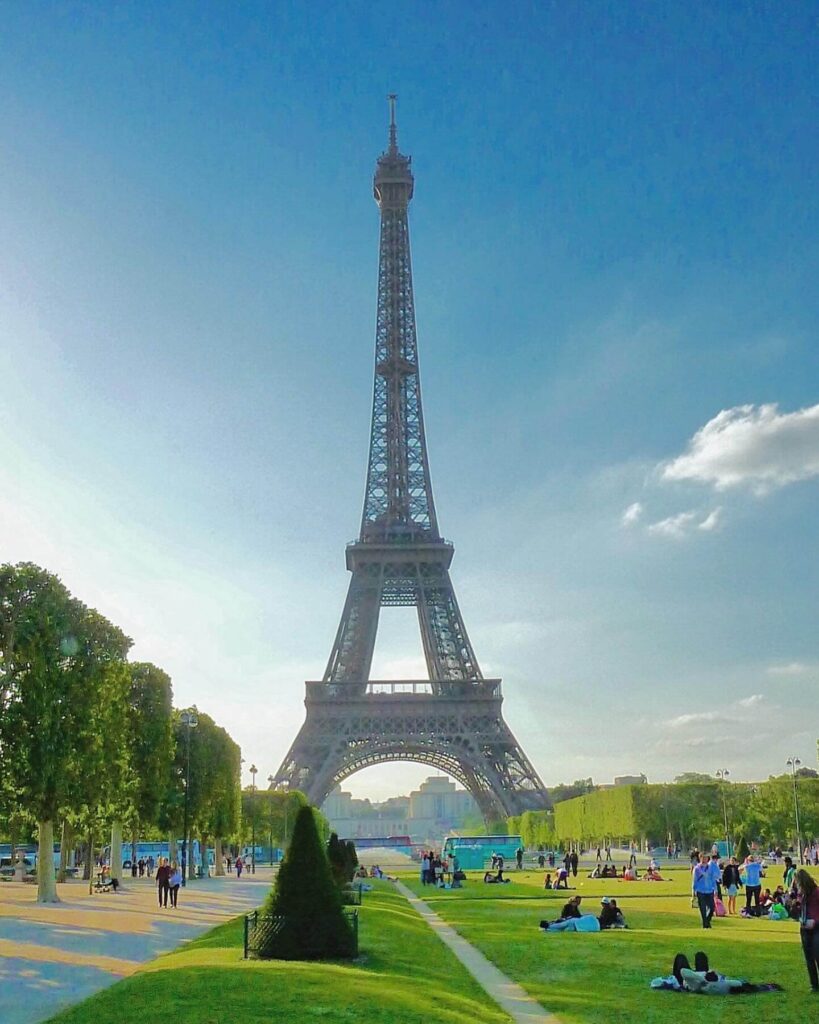 Eiffel Tower viewed from Champ de Mars with people sitting on the grass in Paris