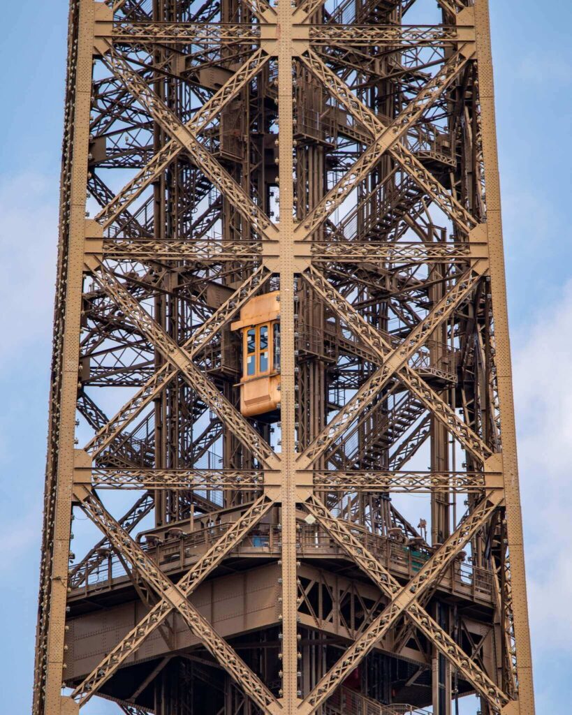 Visitors inside the Eiffel Tower elevator going up through the structure