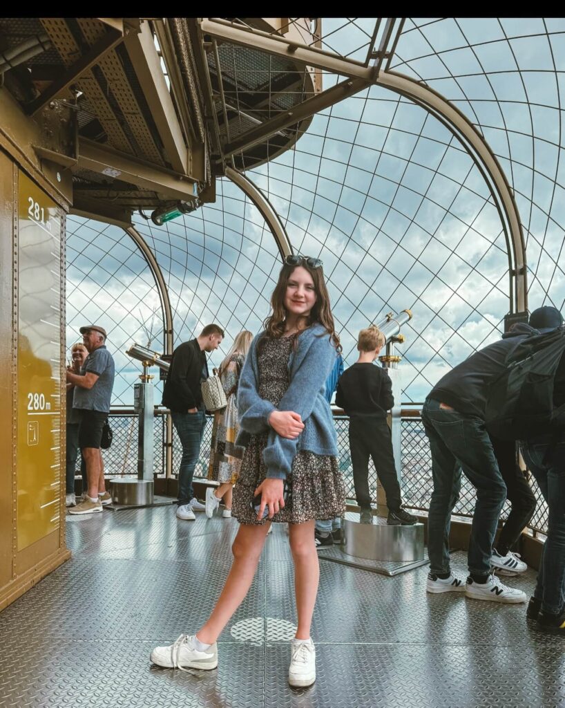 Crowded Eiffel Tower summit observation deck with visitors waiting for views
