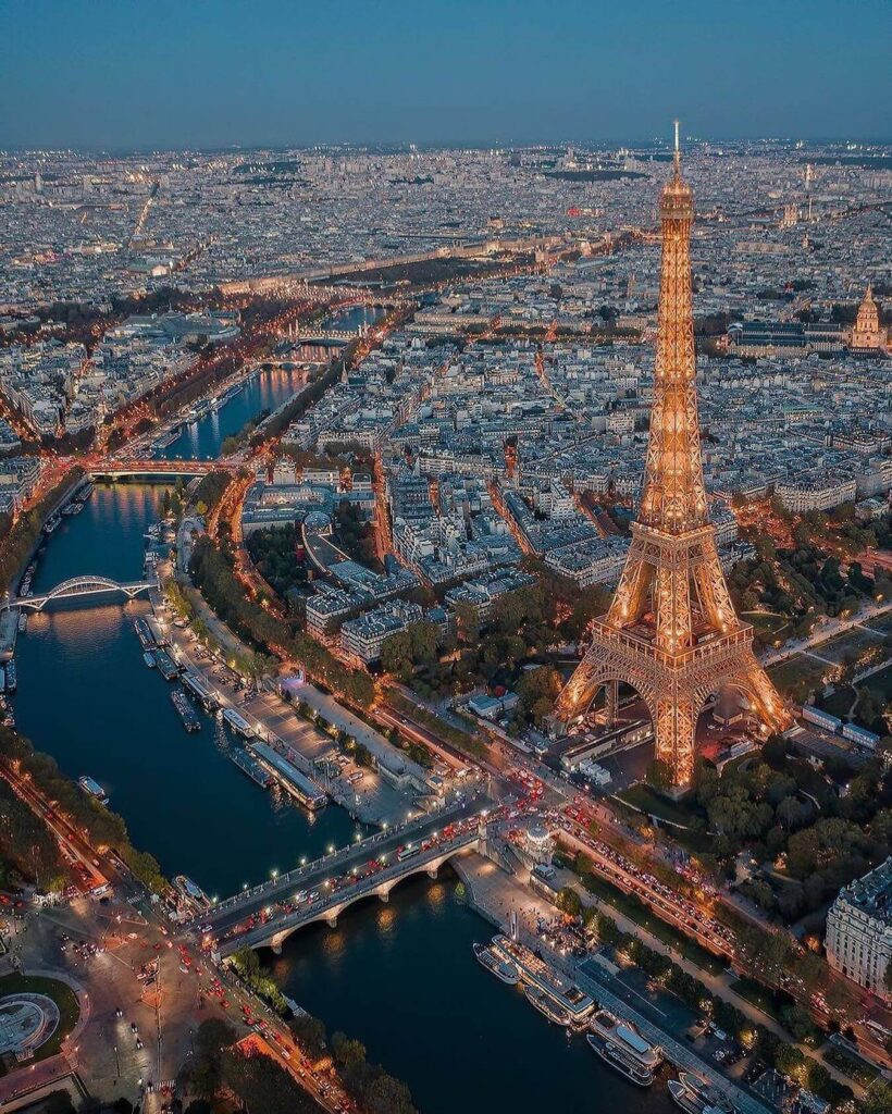 Wide aerial view of Paris from the top of the Eiffel Tower showing distant city details