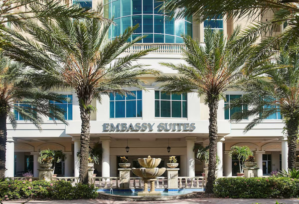 Exterior and lobby view of Embassy Suites by Hilton Tampa Downtown Convention Center featuring modern architecture, spacious upscale interiors, palm-lined surroundings, and convenient access to Tampa’s convention district and waterfront.