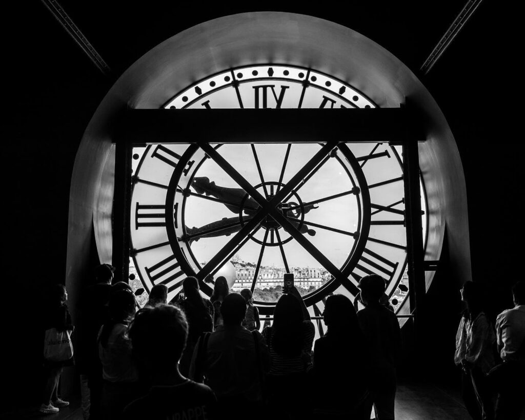 Visitors taking photos near the giant clock windows at Musée d'Orsay
