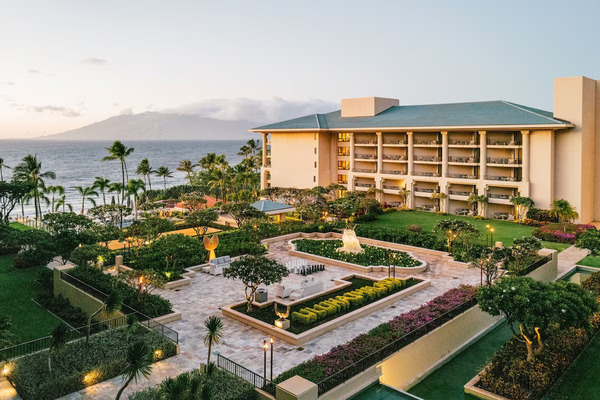 Exterior view of Four Seasons Resort Maui at Wailea featuring luxury oceanfront suites, palm trees, and panoramic Pacific Ocean views at sunset.