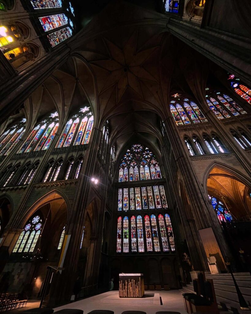 Visitor photographing stained glass inside Metz Cathedral