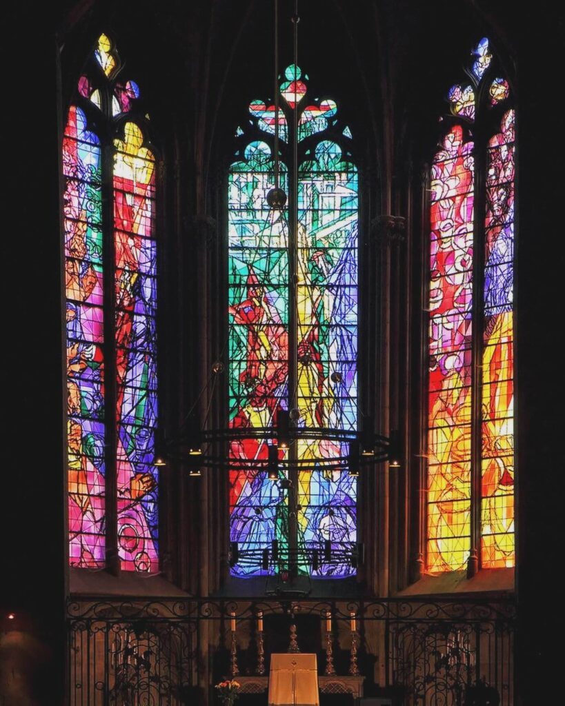 Visitor admiring stained glass inside Metz Cathedral