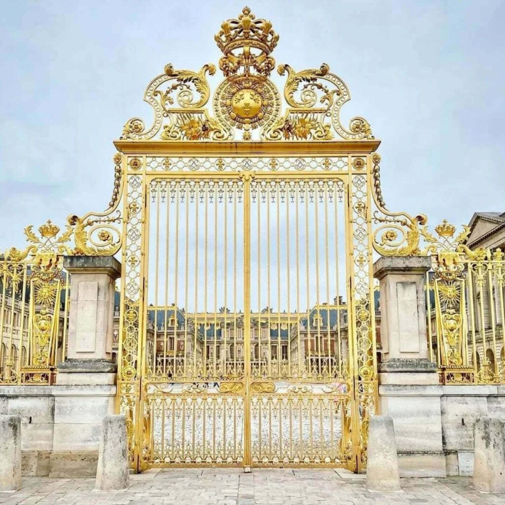 Front view of the Palace of Versailles with golden gates and large courtyard in France