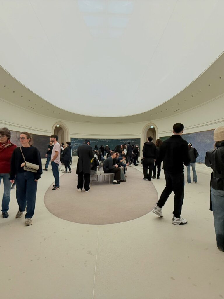 Visitor sitting quietly inside Monet Water Lilies room