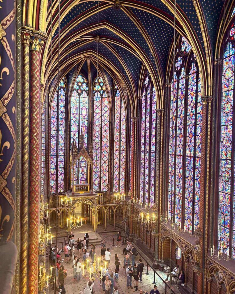 Visitors sitting along the benches inside Sainte-Chapelle upper chapel