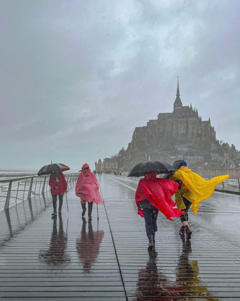 Visitors walking across tidal flats near Mont Saint Michel