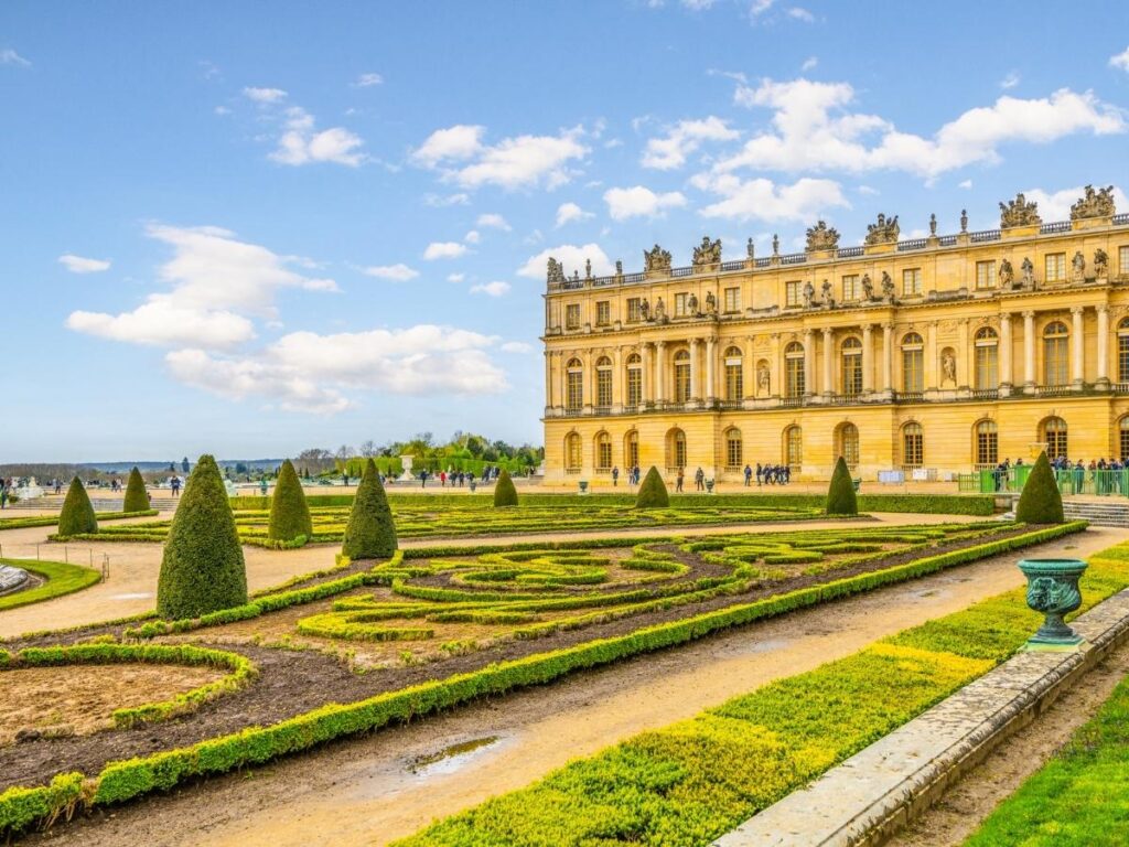 Visitors walking along tree-lined pathways in the Versailles gardens
