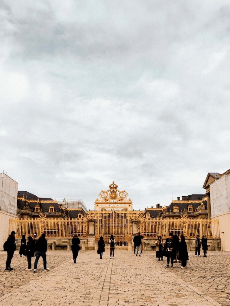 Entrance area at the Palace of Versailles with visitors entering through security gates