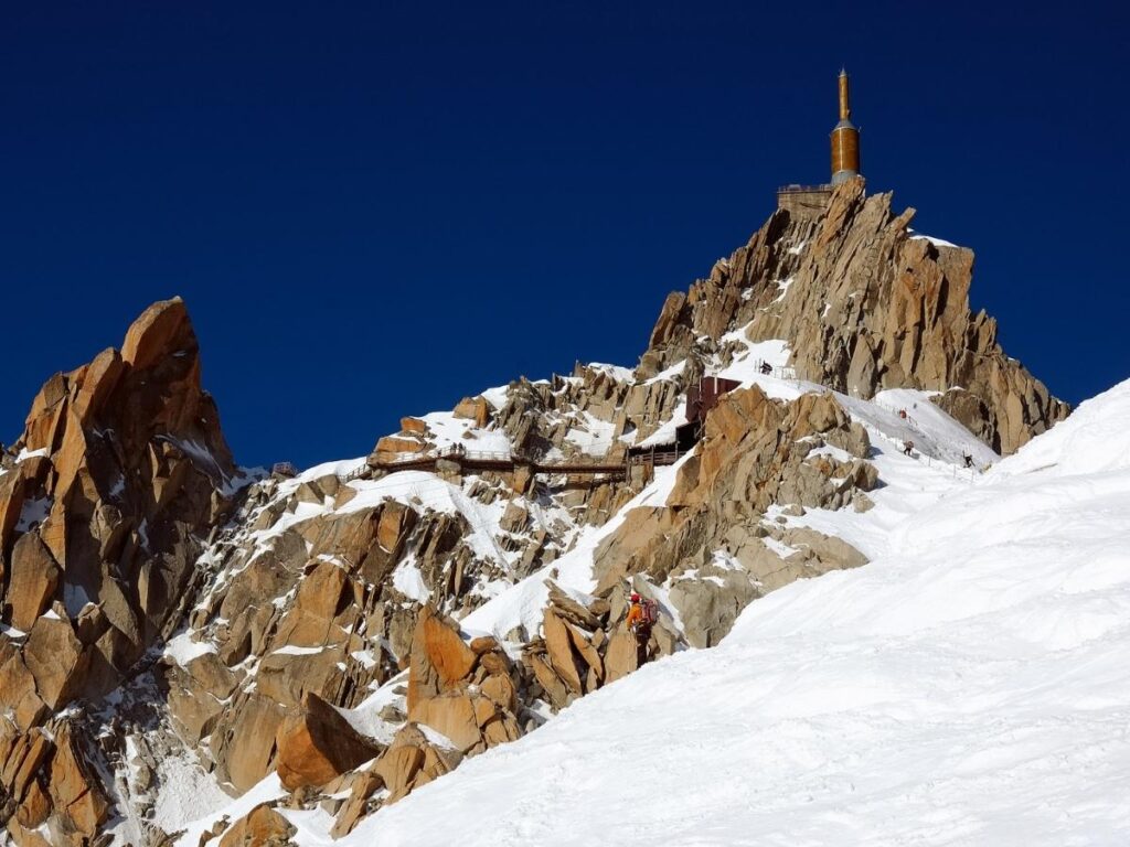 Visitors arriving at the Aiguille du Midi summit station surrounded by Alpine peaks