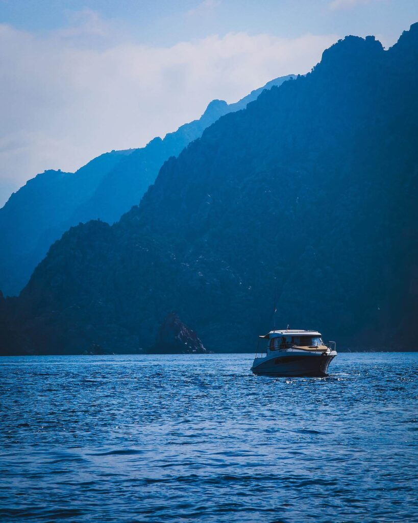 Boat exploring the dramatic coastline of Scandola Nature Reserve in Corsica