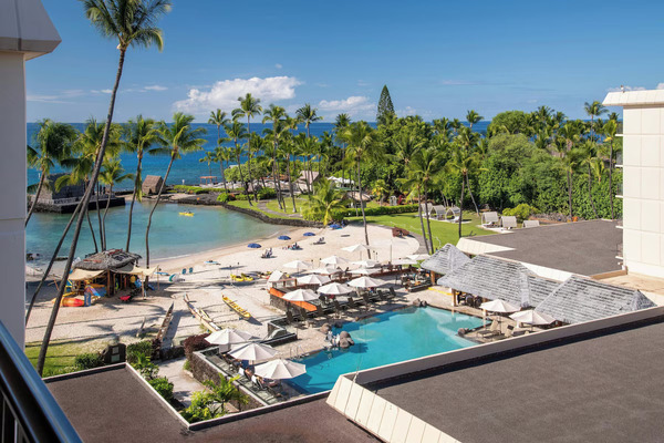 Oceanfront view of Courtyard King Kamehameha's Kona Beach Hotel in Kailua-Kona, Hawaii, featuring beachfront access, tropical palm trees, modern accommodations, and scenic views of Kailua Bay.