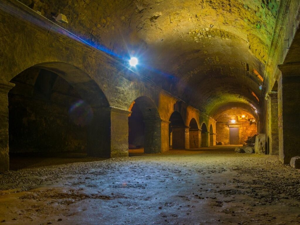Atmospheric underground gallery with vaulted stone ceilings.