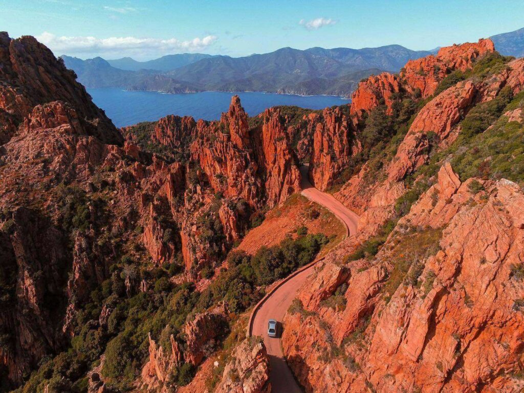 The D81 road winding through the red rock formations of the Calanques de Piana